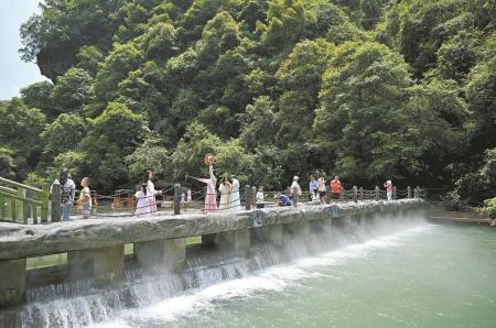 　　7月9日，游客在鹤峰县屏山峡谷游玩。
　　屏山峡谷位于湖北省恩施土家族苗族自治州鹤峰县。峡谷两岸为陡峭的绝壁，峰峦与谷底河面高差超过千米。峡谷中有著名的狭窄通道“五尺门”，仅容小船通过，抬头可见绵延的“一线天”景观。谷底水流清澈，船行其上时，从特定角度看仿佛悬浮空中。独特的峡谷地貌和清澈的水体景观，使屏山峡谷成为吸引众多游客的观光目的地。      新华社发 （宋文 摄）